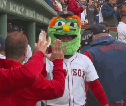 A Man Wearing A Green Mascot Mask And A Boston Jersey High Fives Another Man GIF