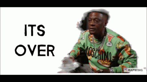 A Man Wearing A Green Moschino Sweater Is Sitting In Front Of A Sign That Says Its Over GIF