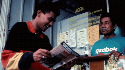 A Man Wearing A Green Reebok Shirt Stands In Front Of A Window GIF