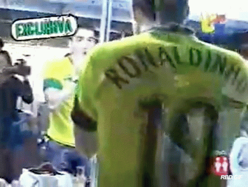 A Man Wearing A Green Ronaldinho Jersey Stands In Front Of A Camera GIF
