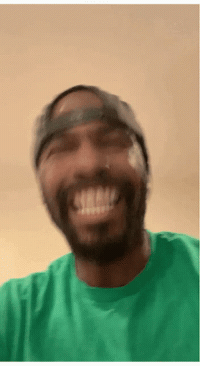 A Man Wearing A Green Shirt And A Hat Smiles GIF