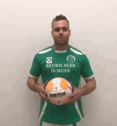A Man Wearing A Green Shirt Is Holding A Soccer Ball . GIF