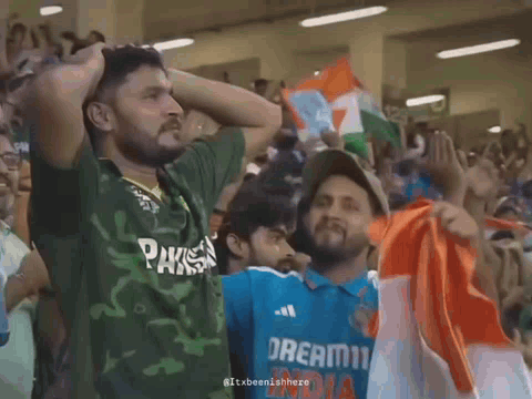A Man Wearing A Green Shirt That Says Pakistan Is Standing Next To Another Man Wearing A Blue Shirt That Says Dream11 In GIF