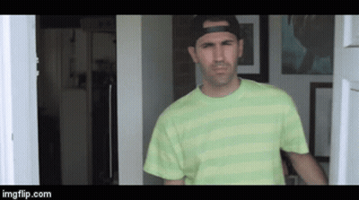 A Man Wearing A Green Striped Shirt And A Black Hat Is Standing In A Doorway .. GIF