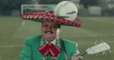 A Man Wearing A Green Suit And Sombrero Is Playing A Guitar . GIF