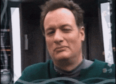 A Man Wearing A Green Sweater Is Looking At The Camera With His Eyes Closed GIF