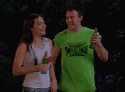 A Man Wearing A Green T-Shirt That Says " Crack " Holds A Bottle Of Beer Next To A Woman GIF