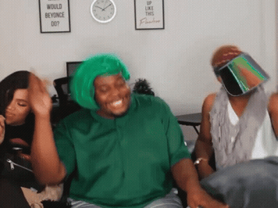 A Man Wearing A Green Wig Is Laughing In Front Of A Sign That Says Would Beyonce Do GIF