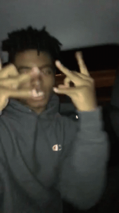A Man Wearing A Grey Champion Hoodie Makes A Peace Sign GIF