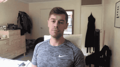 a man wearing a grey nike shirt stands in a room