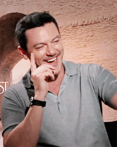 A Man Wearing A Grey Shirt And A Black Watch Is Smiling GIF