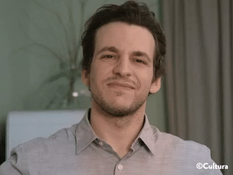 A Man Wearing A Grey Shirt Is Smiling With The Word Cultura On The Bottom Right GIF