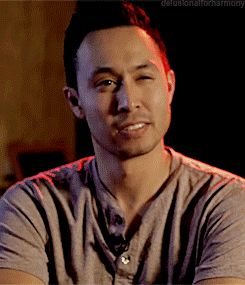 A Man Wearing A Grey Shirt Is Smiling With The Words Delusionalforharmony Below Him GIF