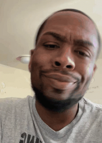 A Man Wearing A Grey Shirt With The Word Smart On It Looks At The Camera GIF