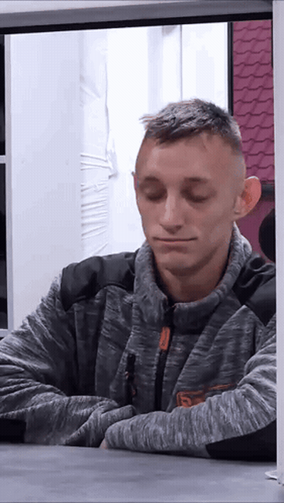 A Man Wearing A Grey Sweater With The Letter S On It GIF