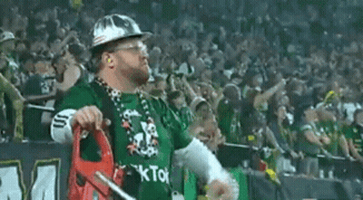 A Man Wearing A Hard Hat And A Green Shirt With The Word Kto On It Is Standing In Front Of A Crowd . GIF