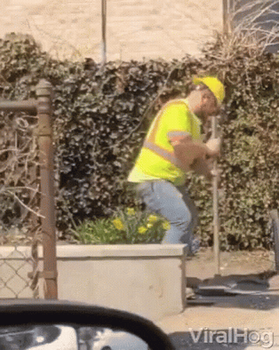 A Man Wearing A Hard Hat And Safety Vest Is Digging In The Ground GIF