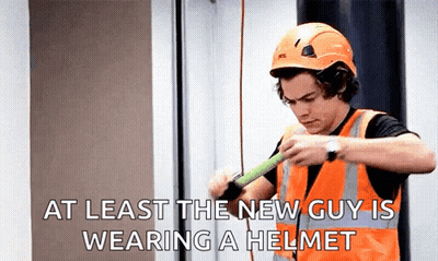 A Man Wearing A Hard Hat And Safety Vest Is Holding A Tape Measure . GIF