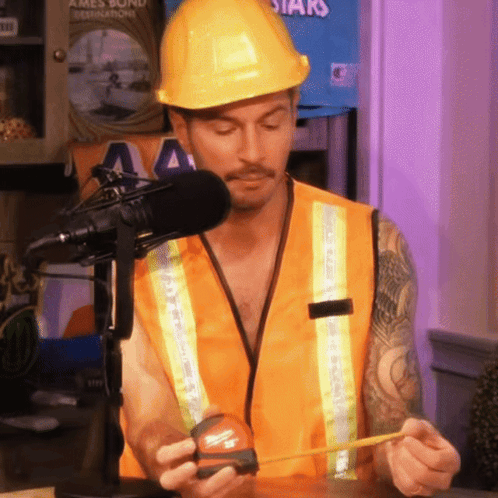 A Man Wearing A Hard Hat And Safety Vest Is Measuring Something GIF
