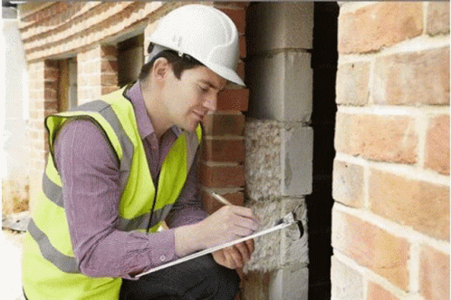 A Man Wearing A Hard Hat Is Writing On A Clipboard . GIF