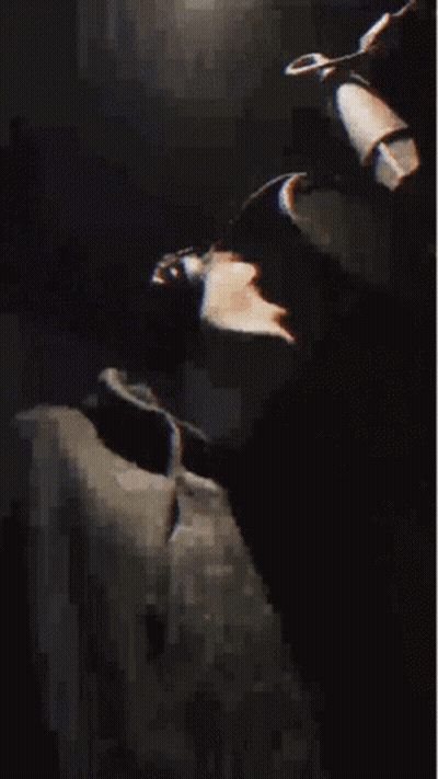 A Man Wearing A Hat And A Black Jacket Is Making A Funny Face . GIF