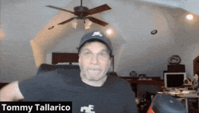 A Man Wearing A Hat And A Black Shirt With The Name Tommy Tallarico On It GIF