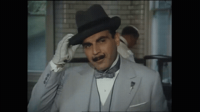 A Man Wearing A Hat And A Bow Tie Adjusts His Hat GIF