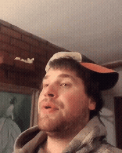 A Man Wearing A Hat And A Hoodie Is Making A Face GIF