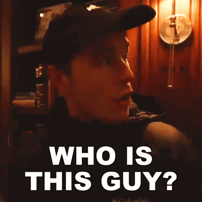 A Man Wearing A Hat And A Jacket Is Asking Who Is This Guy GIF