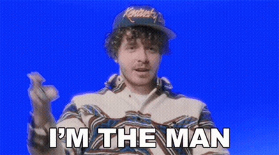 A Man Wearing A Hat And A Jacket Is Saying `` I 'M The Man '' While Holding A Baseball . GIF