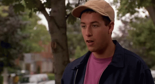 A Man Wearing A Hat And A Jacket Is Standing Under A Tree . GIF