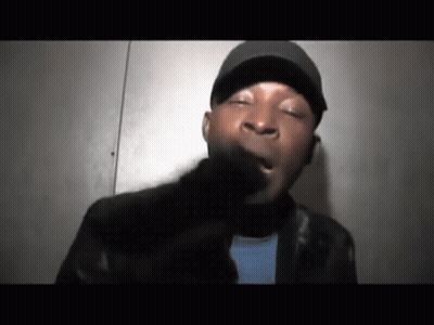 A Man Wearing A Hat And A Leather Jacket Is Making A Face . GIF