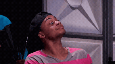 A Man Wearing A Hat And A Pink And Gray Striped Shirt Is Making A Face . GIF