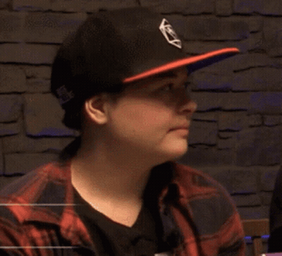 A Man Wearing A Hat And A Plaid Shirt Is Reading A Book And Smiling . GIF