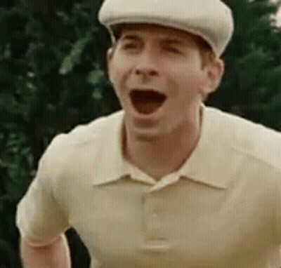 A Man Wearing A Hat And A Polo Shirt Is Making A Funny Face . GIF