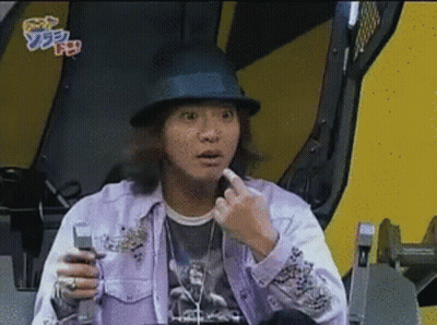 A Man Wearing A Hat And A Purple Shirt Holds A Cell Phone In His Hand GIF