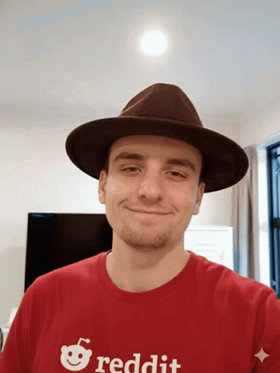 A Man Wearing A Hat And A Reddit Shirt Smiles For The Camera GIF
