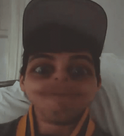 A Man Wearing A Hat And A Scarf Makes A Funny Face GIF