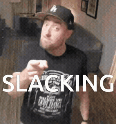 A Man Wearing A Hat And A Shirt That Says Slacking Is Pointing At The Camera GIF