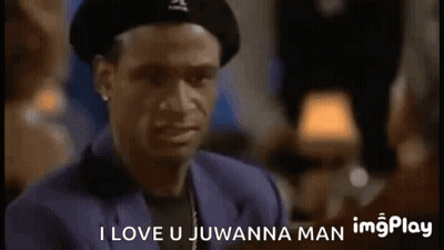 A Man Wearing A Hat And A Suit Is Talking To Another Man In A Bar . GIF