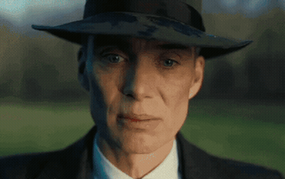 A Man Wearing A Hat And A Suit Looks At The Camera GIF
