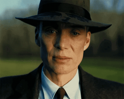 A Man Wearing A Hat And A Suit Looks At The Camera GIF