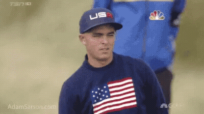 A Man Wearing A Hat And A Sweater With An American Flag On It GIF