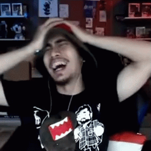 A Man Wearing A Hat And A T-Shirt With A Picture Of A Man With A Beard Is Laughing . GIF