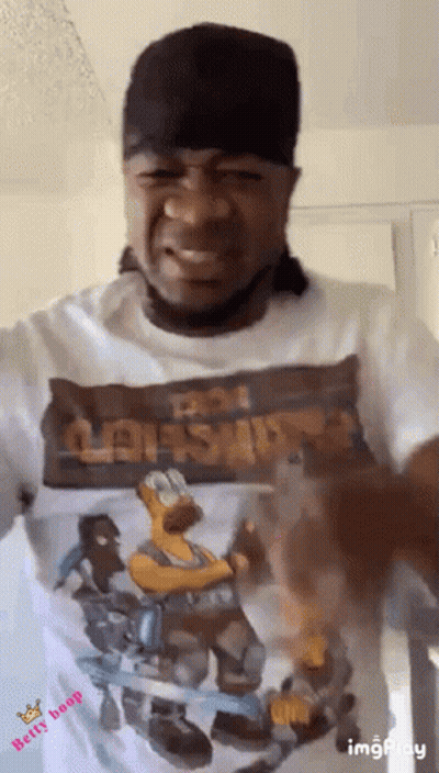 A Man Wearing A Hat And A T-Shirt With A Picture Of Homer Simpson On It . GIF