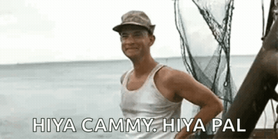 A Man Wearing A Hat And A Tank Top Is Standing On A Boat In The Water . GIF