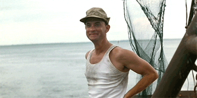 A Man Wearing A Hat And A Tank Top Is Standing On A Boat Near The Ocean GIF