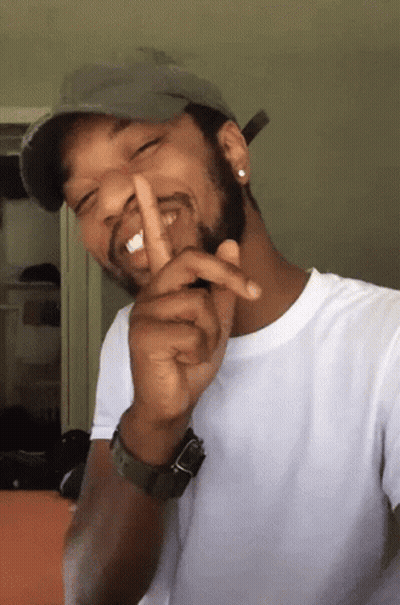 A Man Wearing A Hat And A Watch Is Making A Shhh Gesture GIF