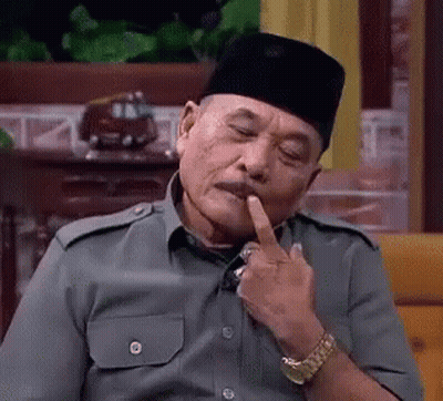 A Man Wearing A Hat And A Watch Is Sitting On A Couch With His Finger In His Mouth . GIF