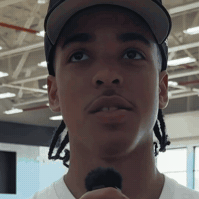 A Man Wearing A Hat And A White Shirt Holds A Microphone In His Hand GIF